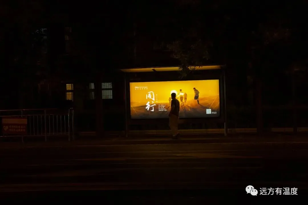 夜晚的公交站台，老人在看着站牌：